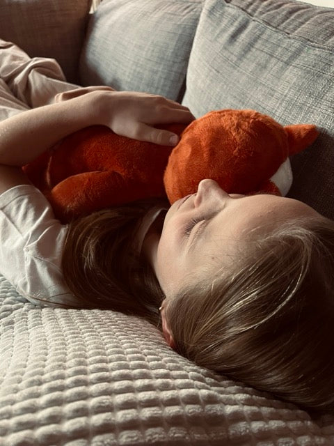 Kind ligt neer met verzwaringsknuffel kiki op haar borst