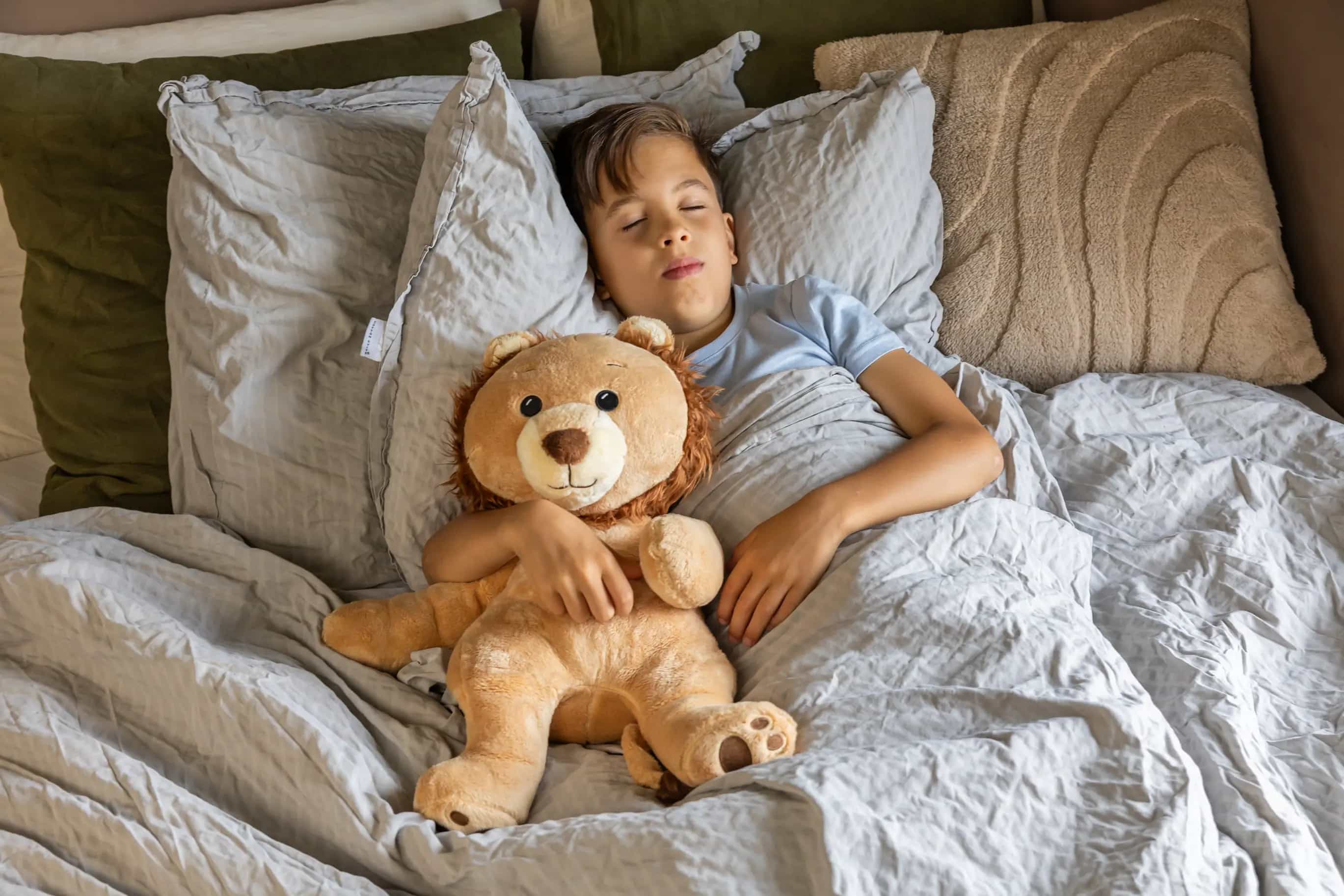 Jongen in bed met KUDL Leeuw Verzwaringsknuffel met Hartslag