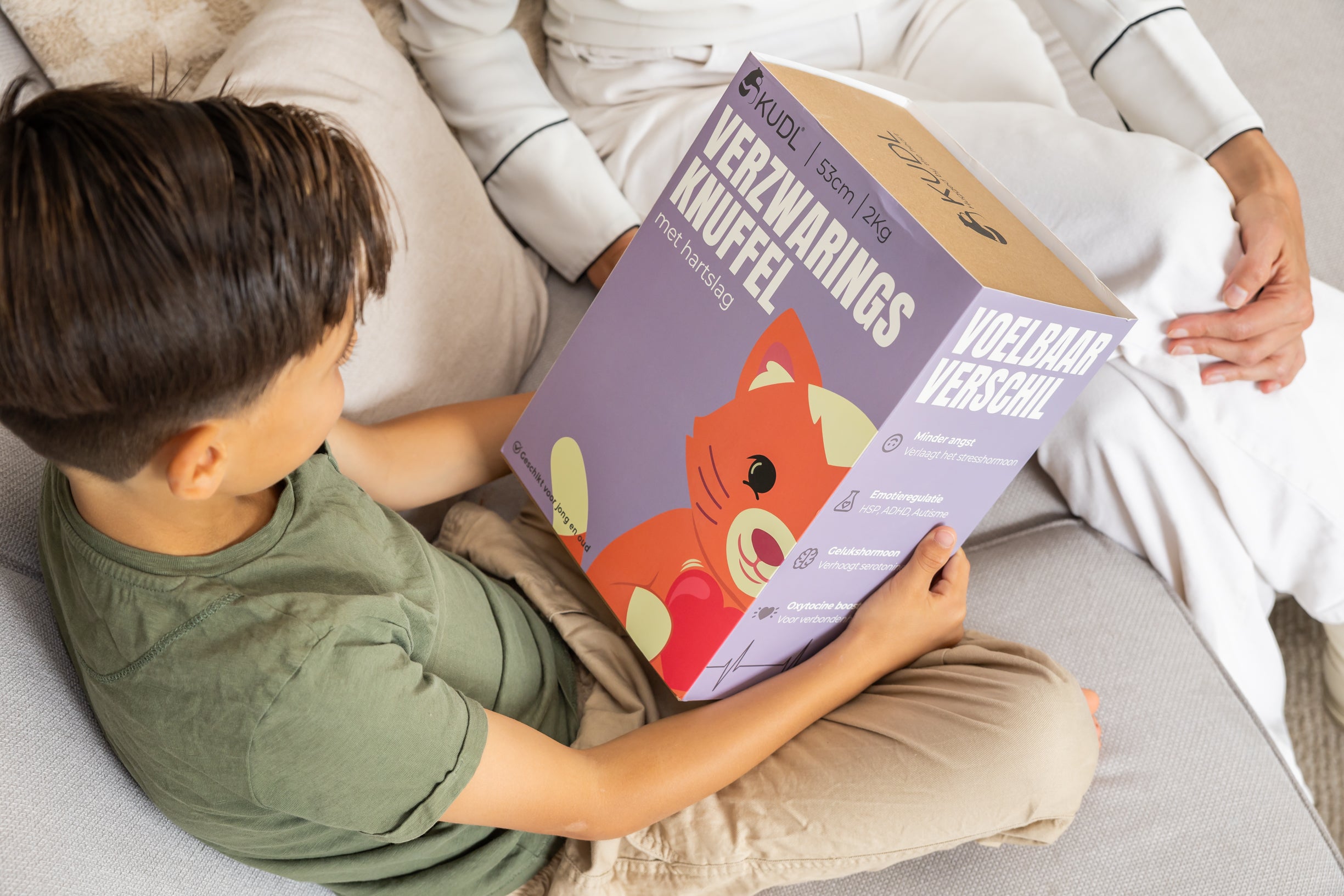 Jongen die de doos van Kiki KUDL Verzwaringsknuffel met Hartslag vast houdt