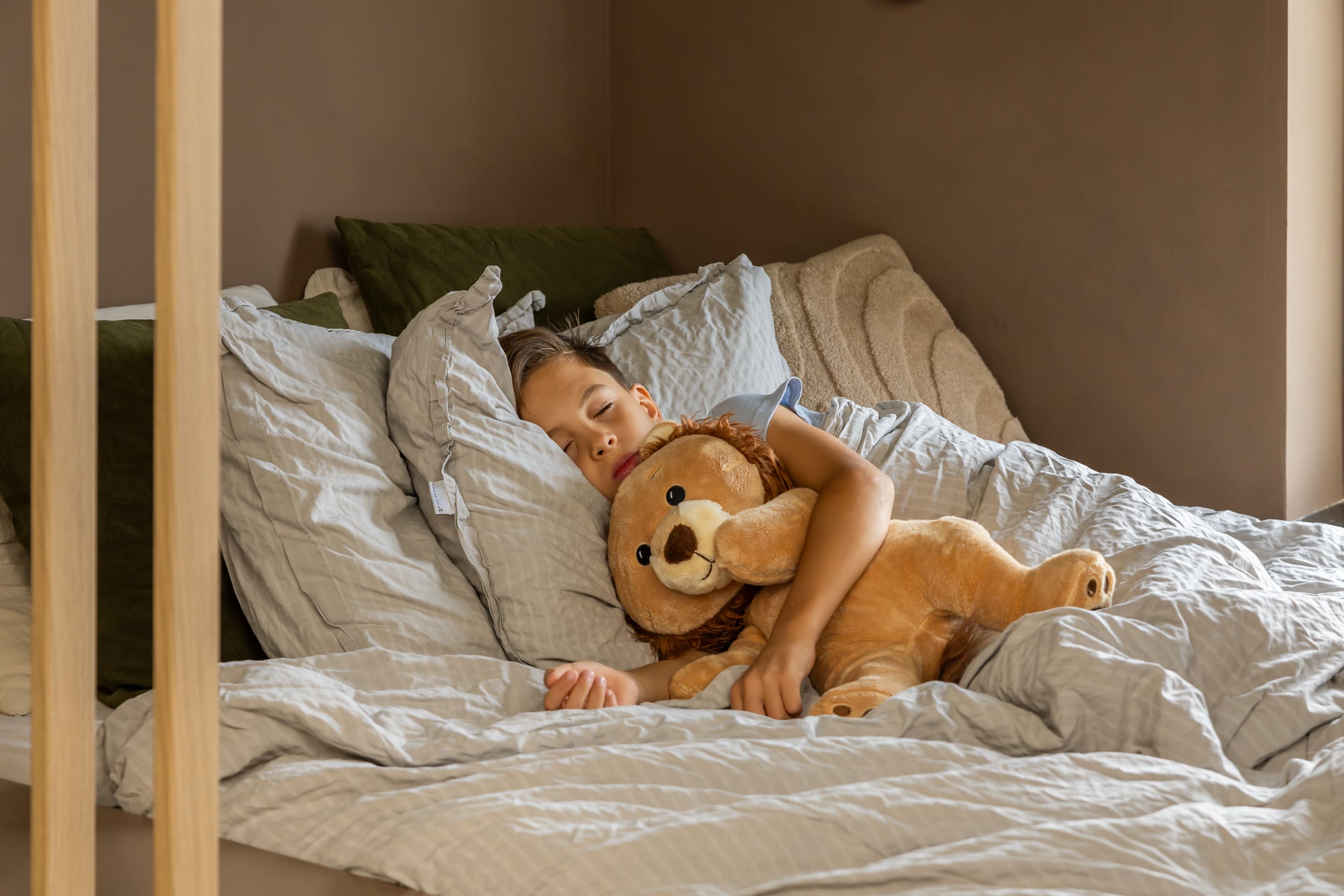 Jongen in bed met KUDL Leeuw Verzwaringsknuffel met Hartslag